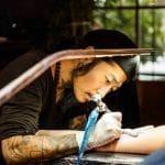 a tattoo artist tattooing a person's arm