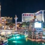 city at night with lot of buildings and a lake shining in turqiouse color